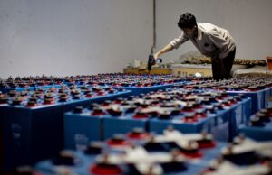 Mann prüft in einem Raum zahlreiche große Batterien mit einem Akkuschrauber